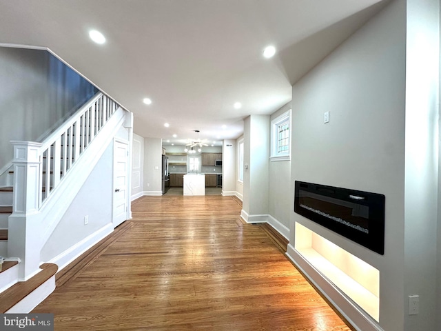 living room with stairway, a glass covered fireplace, wood finished floors, and recessed lighting