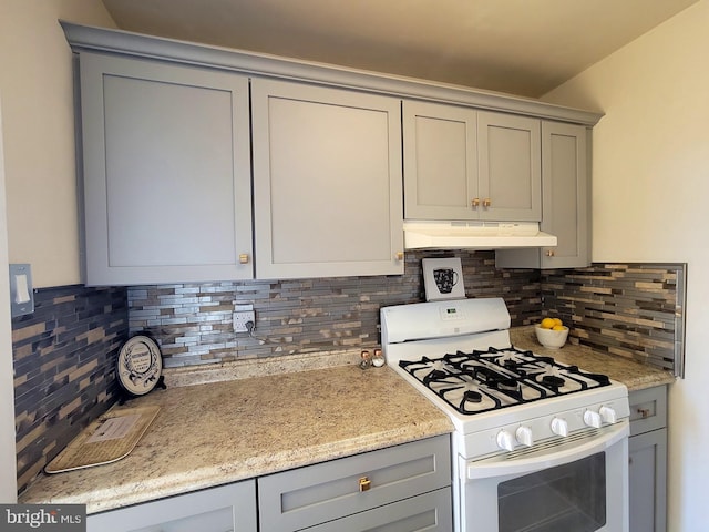 kitchen with under cabinet range hood, white gas range, and gray cabinetry