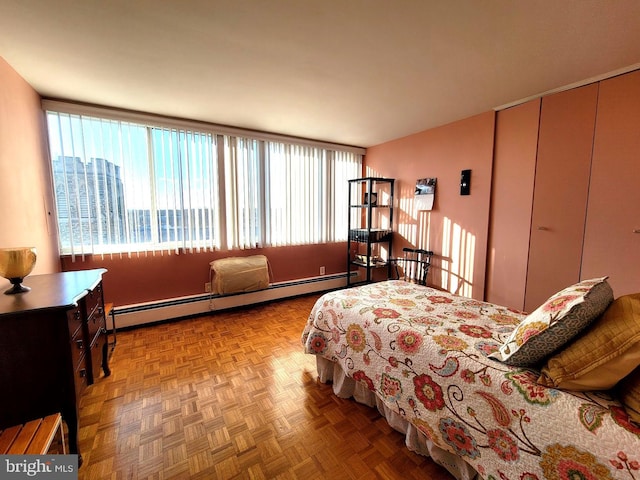 bedroom with a baseboard heating unit, a closet, and multiple windows