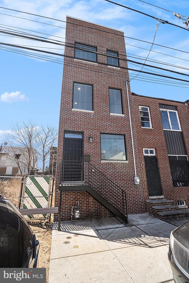 view of front facade with entry steps, fence, and brick siding