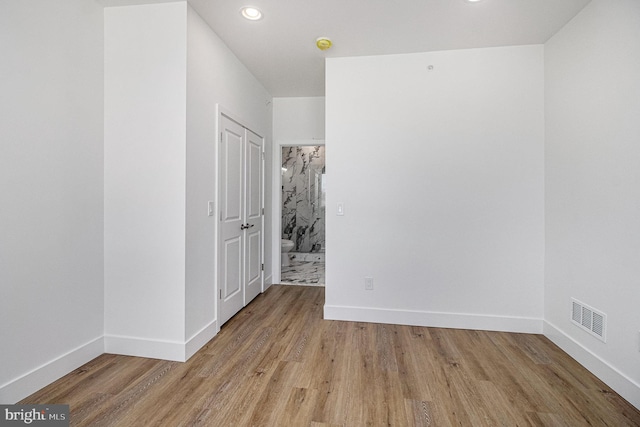 unfurnished room featuring recessed lighting, wood finished floors, visible vents, and baseboards