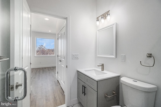 bathroom with baseboards, toilet, wood finished floors, and vanity