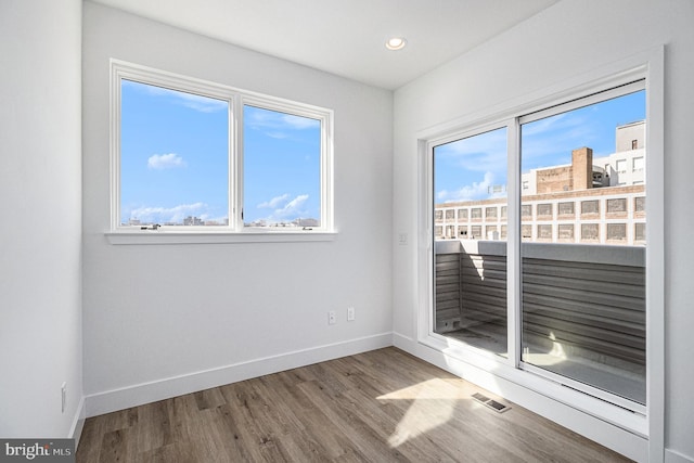 empty room featuring visible vents, recessed lighting, wood finished floors, and baseboards