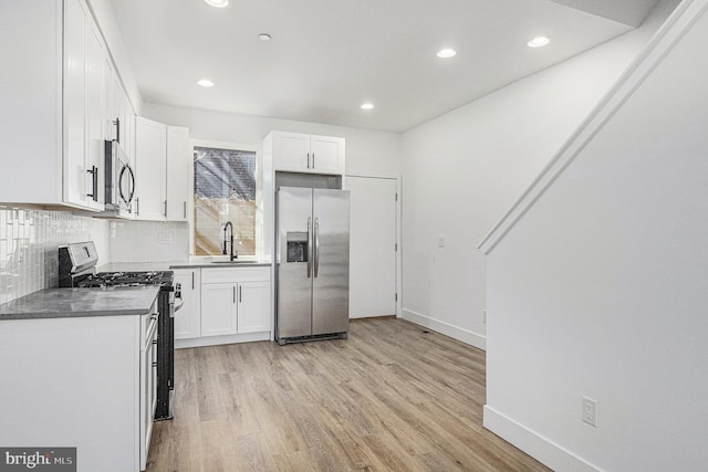 kitchen with a sink, white cabinets, tasteful backsplash, and stainless steel appliances