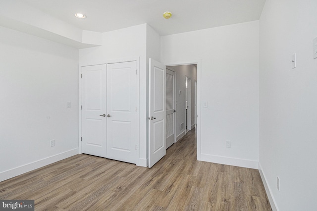 unfurnished bedroom featuring light wood finished floors, recessed lighting, a closet, and baseboards