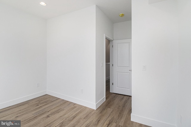 spare room featuring recessed lighting, baseboards, and wood finished floors