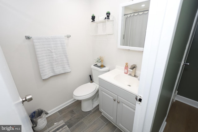 full bathroom featuring wood finish floors, toilet, vanity, and baseboards