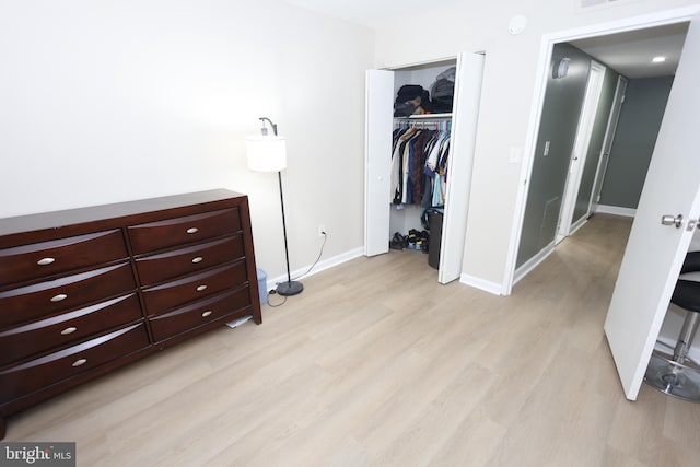 bedroom featuring light wood-type flooring, a closet, and baseboards