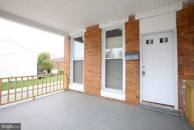 view of exterior entry with covered porch and brick siding