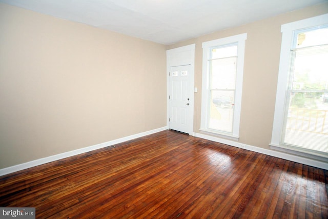 empty room with dark wood-style flooring and baseboards