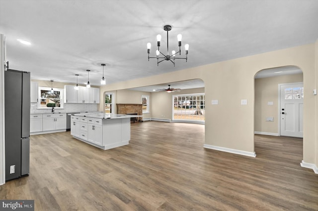 kitchen with a kitchen island, open floor plan, hanging light fixtures, light countertops, and freestanding refrigerator