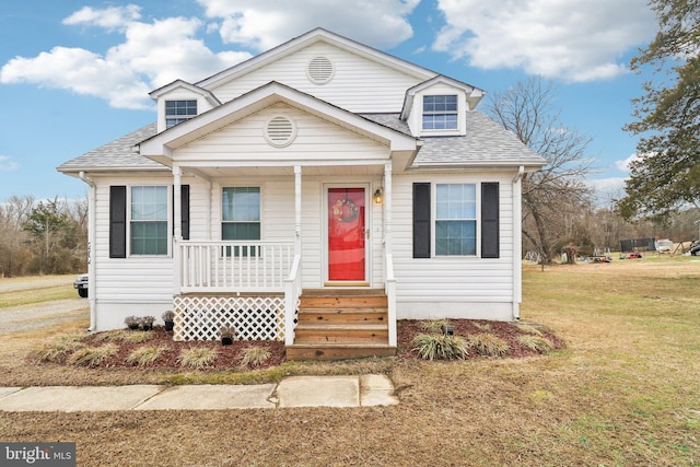 view of front of property with a porch, a shingled roof, and a front lawn