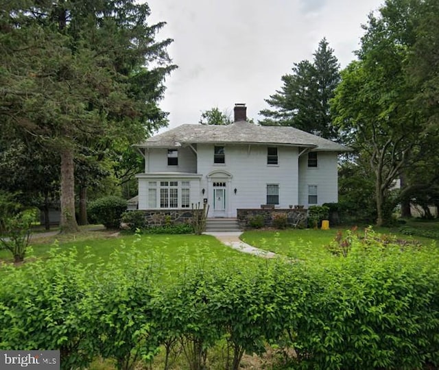 view of front of house featuring a chimney and a front yard