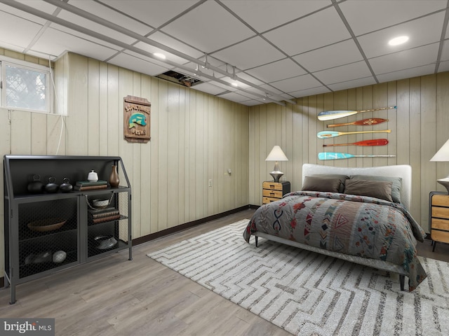 bedroom featuring a drop ceiling and wood finished floors