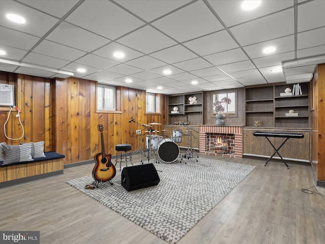 workout area featuring wooden walls, a fireplace, built in features, and wood finished floors