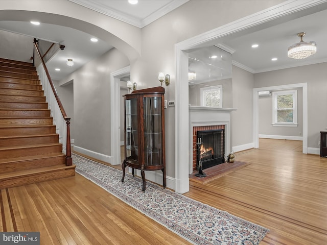 foyer entrance featuring baseboards, arched walkways, wood finished floors, and ornamental molding