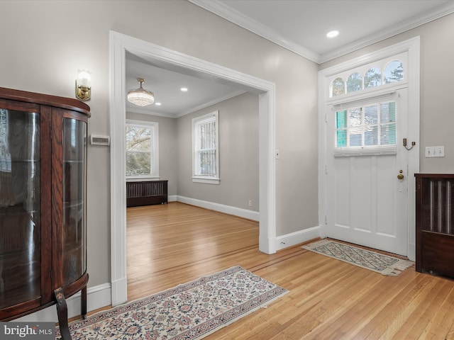 entrance foyer with ornamental molding, radiator, light wood-style floors, and baseboards