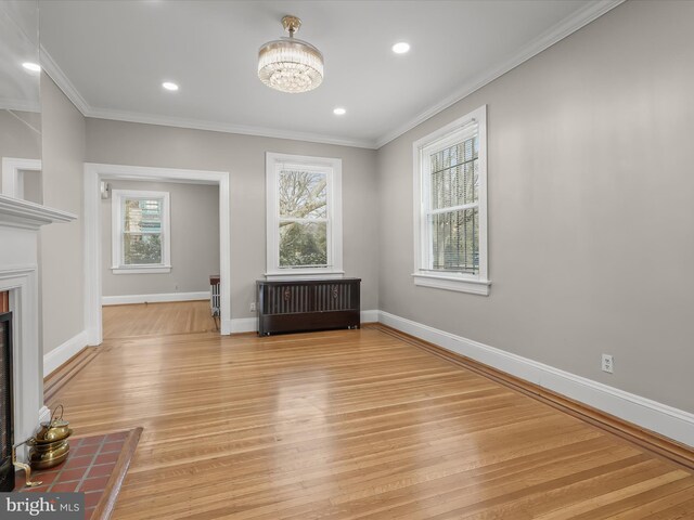 interior space featuring light wood-style flooring, a fireplace, baseboards, and crown molding