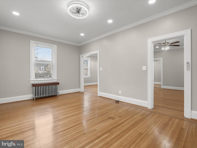 spare room featuring baseboards, ornamental molding, radiator heating unit, and light wood-style floors