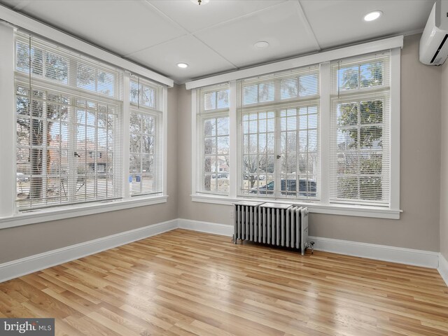 unfurnished sunroom with radiator heating unit and a wall mounted AC