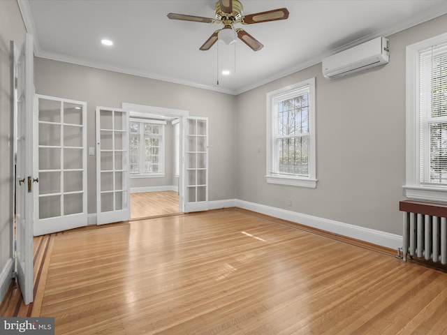 unfurnished room featuring ornamental molding, an AC wall unit, baseboards, and wood finished floors