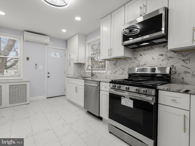 kitchen with white cabinets, a wall unit AC, marble finish floor, stainless steel appliances, and a sink