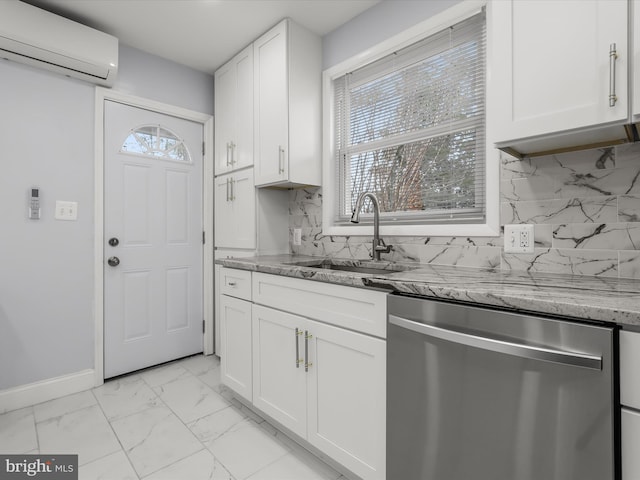 kitchen with marble finish floor, an AC wall unit, stainless steel dishwasher, white cabinetry, and a sink