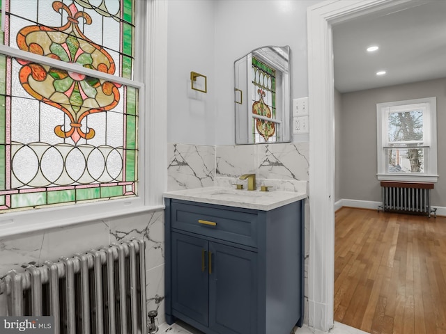 bar with radiator heating unit, backsplash, a sink, and light wood-style flooring