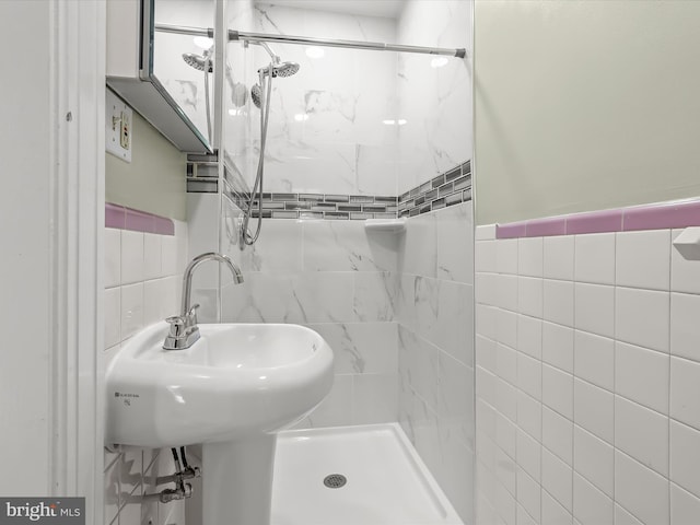 full bathroom featuring a sink, a stall shower, and tile walls