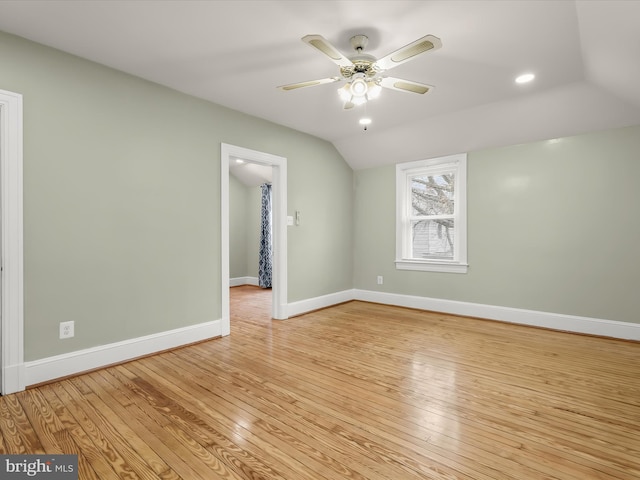 empty room with light wood-style floors, ceiling fan, baseboards, and vaulted ceiling