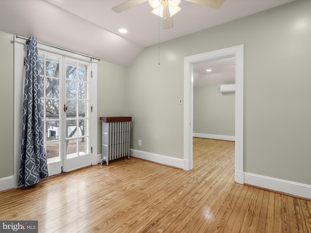 spare room with baseboards, a wall unit AC, hardwood / wood-style floors, and radiator heating unit