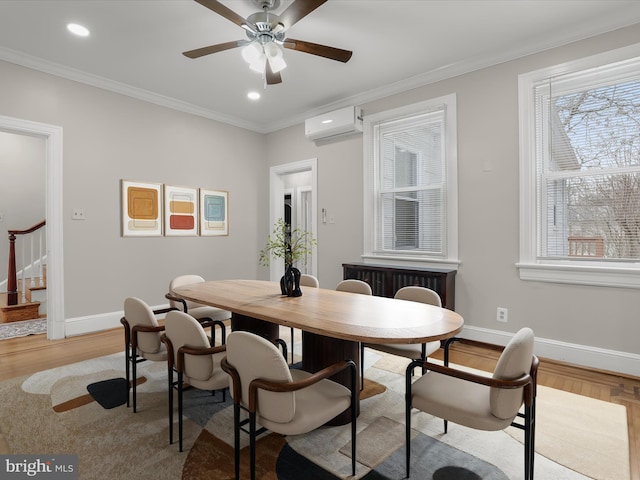 dining space featuring light wood-type flooring, crown molding, baseboards, and a wall mounted AC