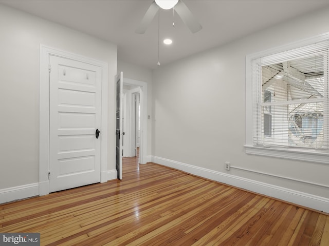 spare room featuring light wood-style floors, baseboards, and a ceiling fan