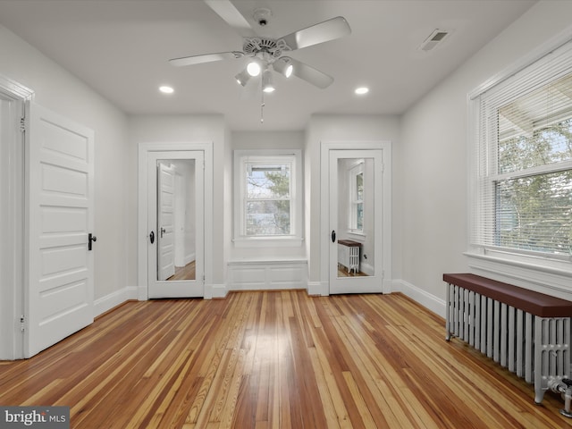 interior space with light wood-style flooring, plenty of natural light, visible vents, and radiator