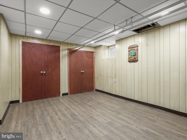 interior space featuring a drop ceiling, baseboards, and wood finished floors