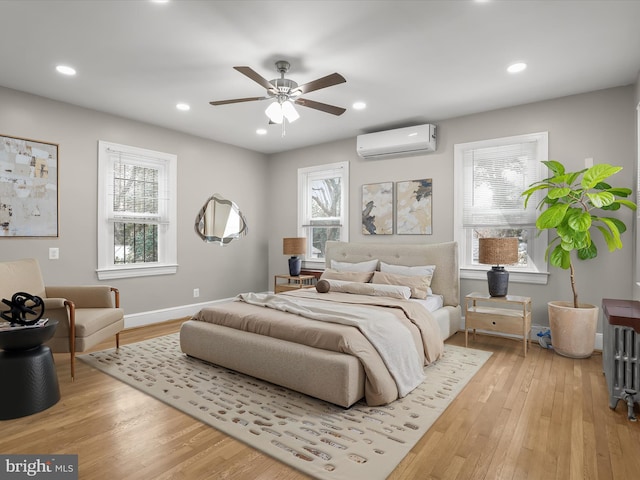 bedroom with recessed lighting, an AC wall unit, ceiling fan, light wood-type flooring, and baseboards