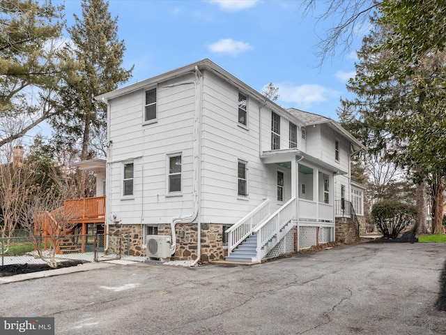 view of side of home featuring stairs, ac unit, covered porch, and fence