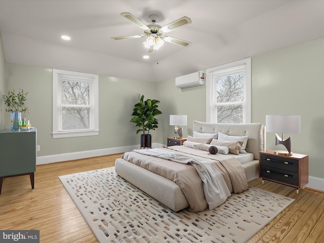 bedroom featuring light wood-style floors, baseboards, an AC wall unit, and recessed lighting