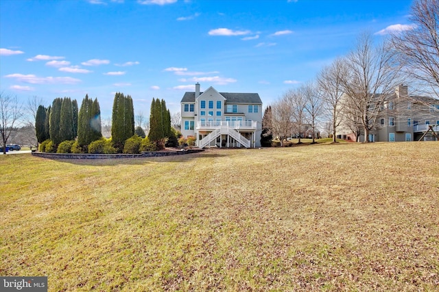 rear view of property with stairs and a yard