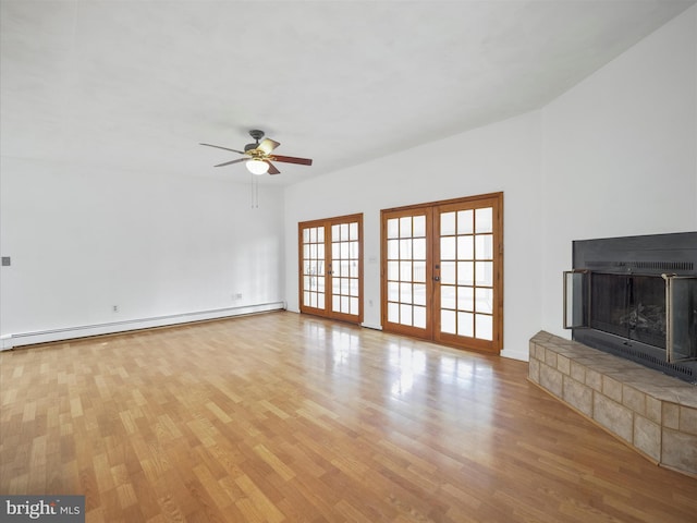 unfurnished living room featuring a fireplace with raised hearth, a ceiling fan, a baseboard radiator, wood finished floors, and french doors