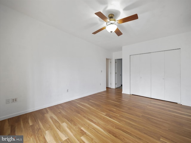 unfurnished bedroom featuring ceiling fan, light wood finished floors, a closet, and baseboards