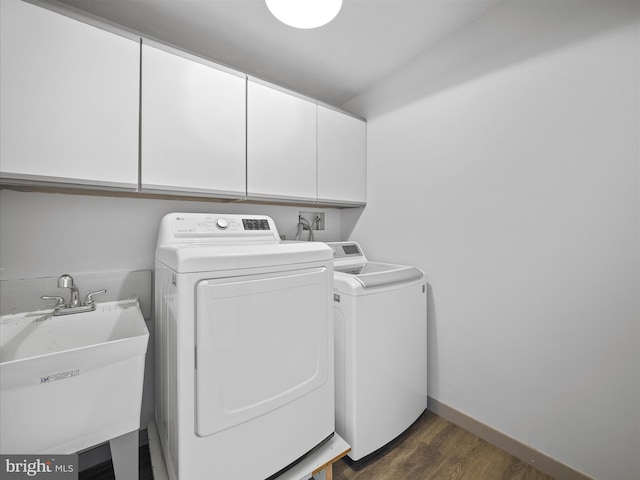 washroom with dark wood-style flooring, cabinet space, a sink, separate washer and dryer, and baseboards