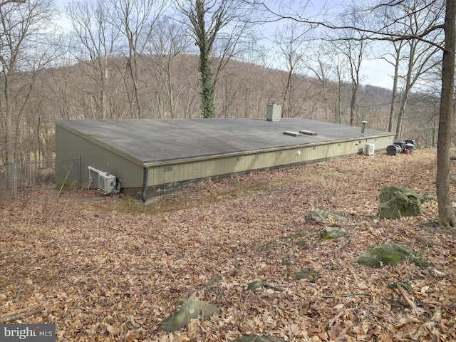 exterior space featuring ac unit and a view of trees