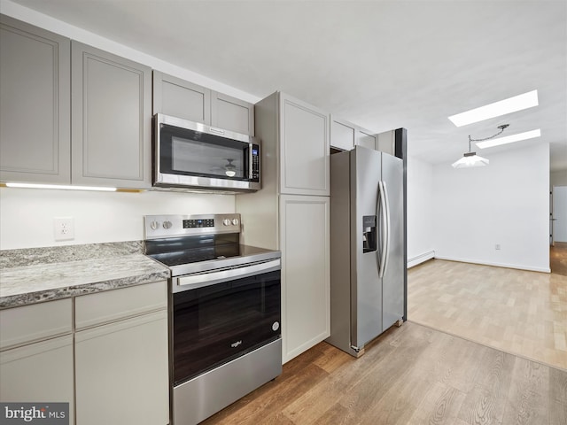 kitchen with a skylight, gray cabinets, appliances with stainless steel finishes, a baseboard heating unit, and light wood-style floors