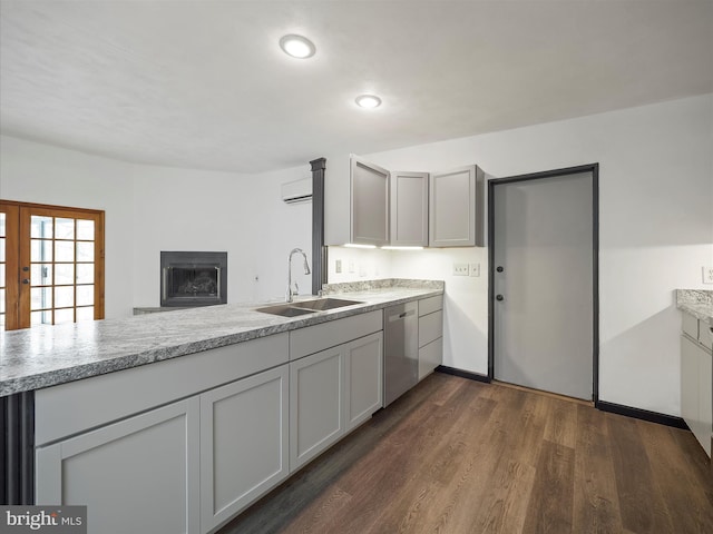 kitchen featuring dishwasher, dark wood-style floors, light countertops, a fireplace, and a sink