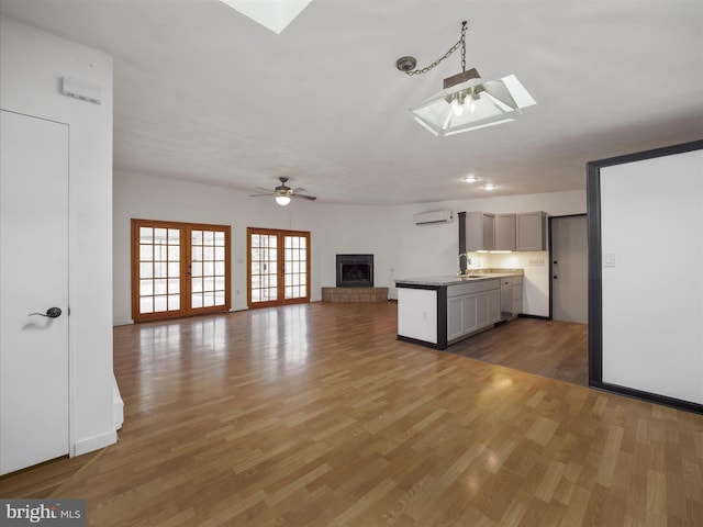 kitchen with a sink, a skylight, a wall unit AC, and light wood-style flooring