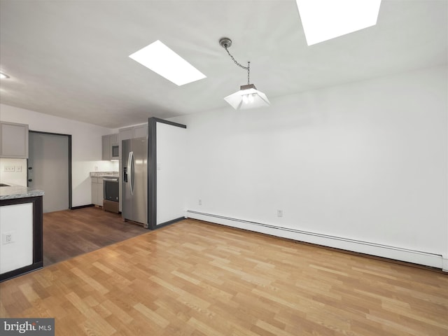 kitchen featuring a skylight, baseboard heating, stainless steel refrigerator with ice dispenser, and gray cabinetry