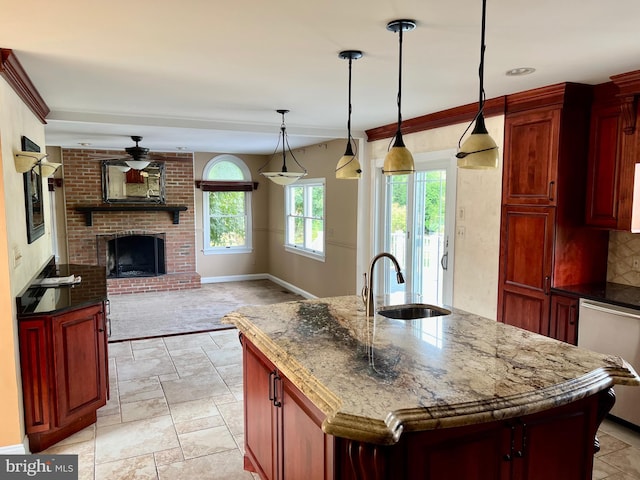 kitchen with reddish brown cabinets, decorative light fixtures, open floor plan, a sink, and an island with sink