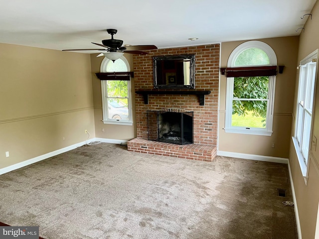 unfurnished living room with a healthy amount of sunlight, a brick fireplace, visible vents, and carpet floors