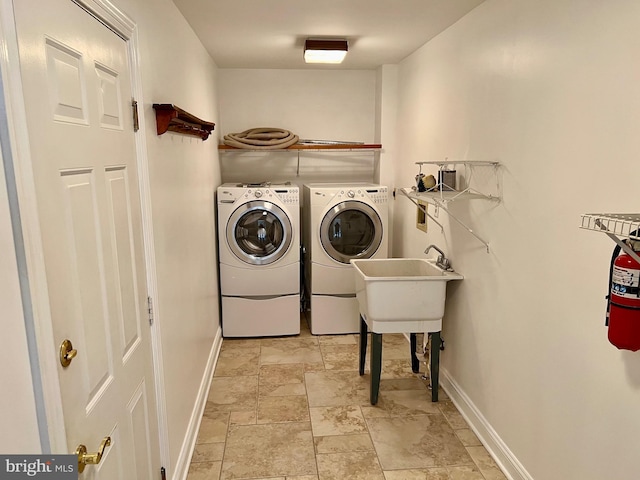 clothes washing area featuring laundry area, stone finish flooring, baseboards, and separate washer and dryer